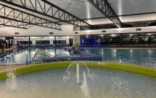 A photo of an indoor swimming pool, showing a water play area and 20m warm water pool