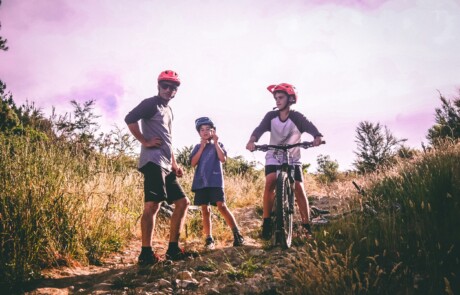 A photo of a man and two children on bikes on a trail